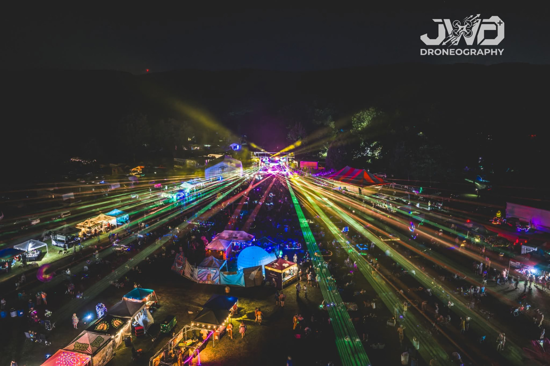 Aerial night view of Terp Float with lasers over the crowd and vendor tents